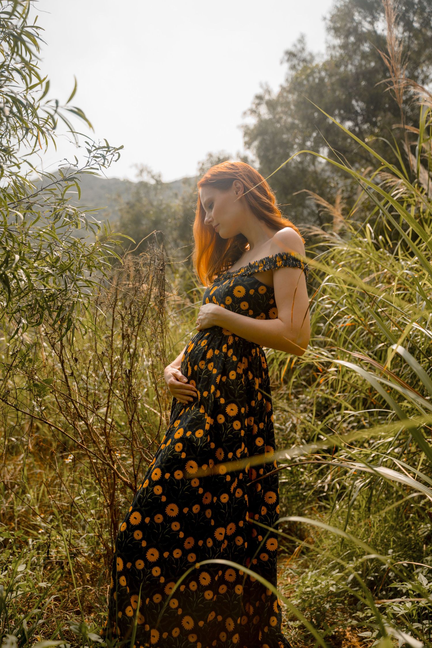 Artistic maternity photos taken in natural setting with golden afternoon light.