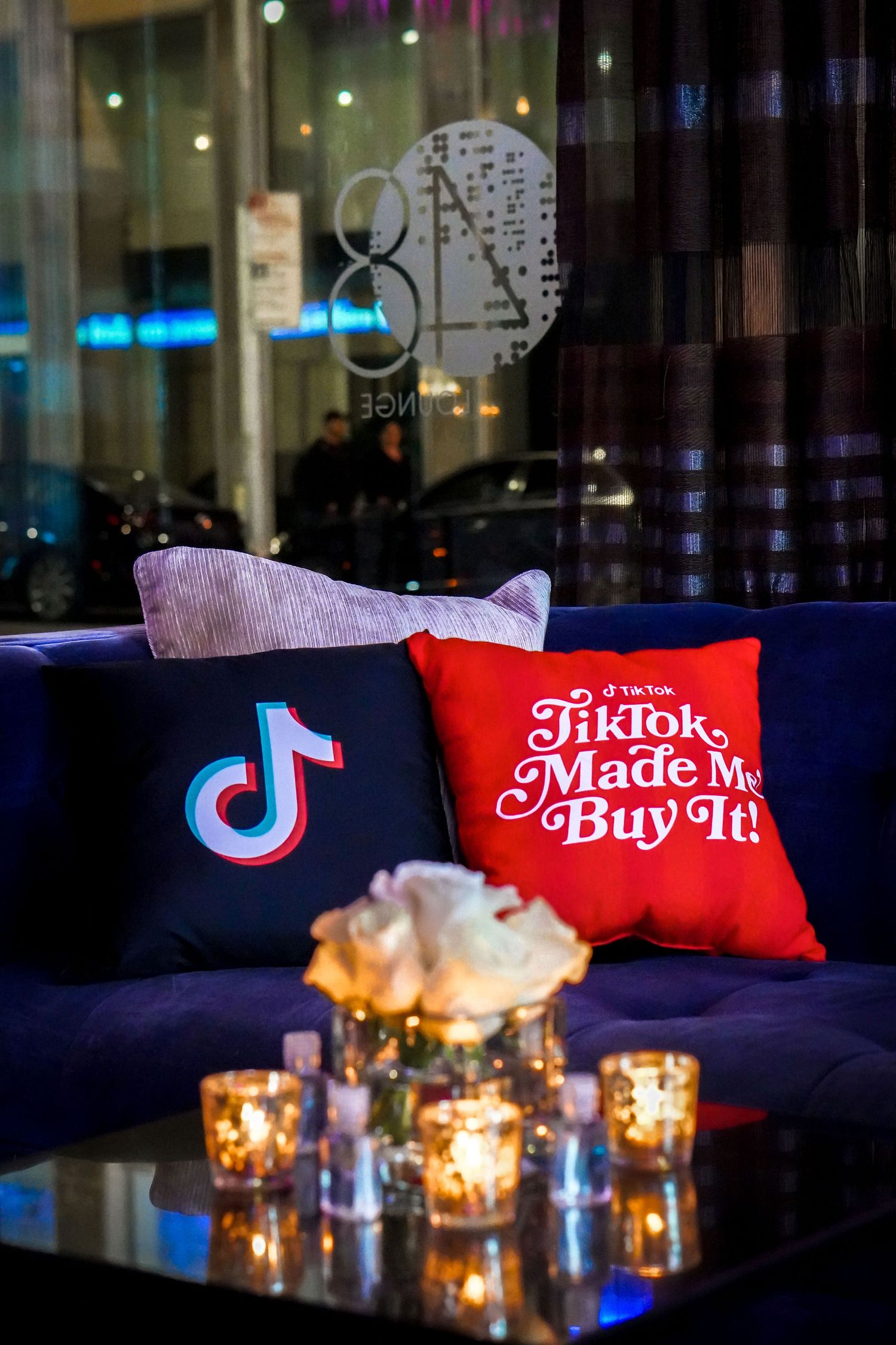 Cozy seating area with TikTok branded throw pillows and glowing candle centerpieces.