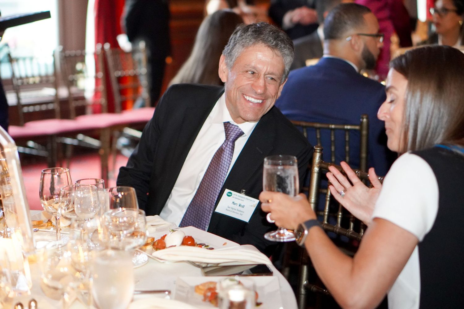 Event guests enjoying conversation at an elegant dinner table setting.