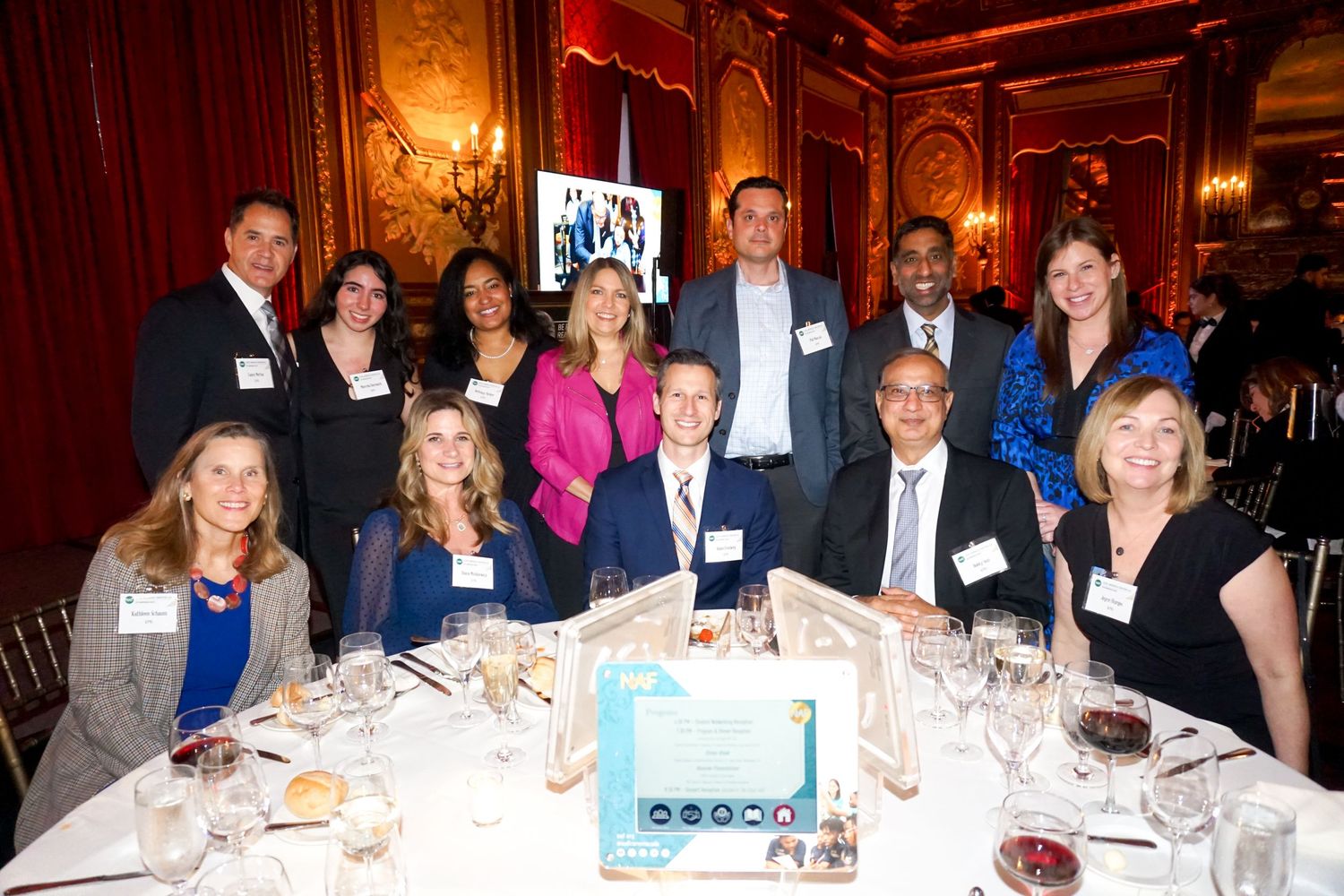 Group of colleagues gathered around an elegant dining table at a formal business event.