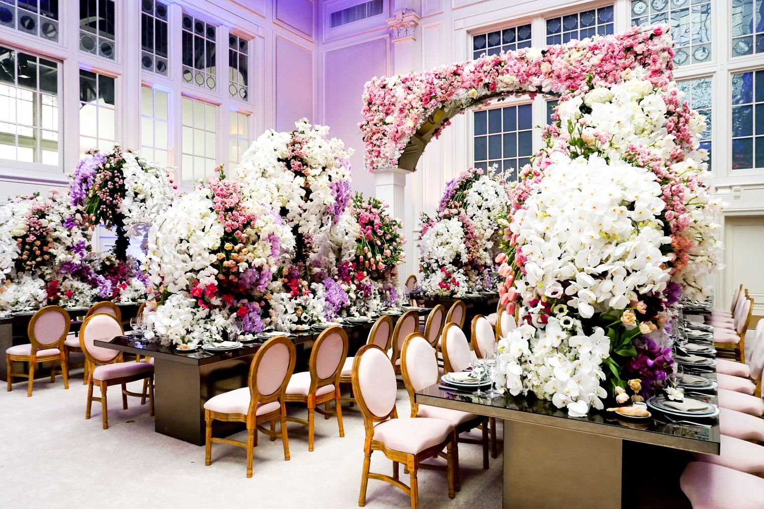 Elegant event space decorated with cascading floral arrangements and upholstered chairs.