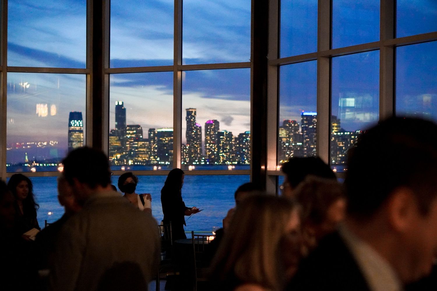 Elegant banquet room with floor-to-ceiling windows showcasing a stunning city skyline view at dusk.