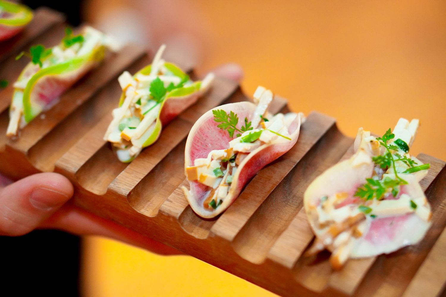 Miniature tacos arranged on wooden serving boards with colorful toppings.