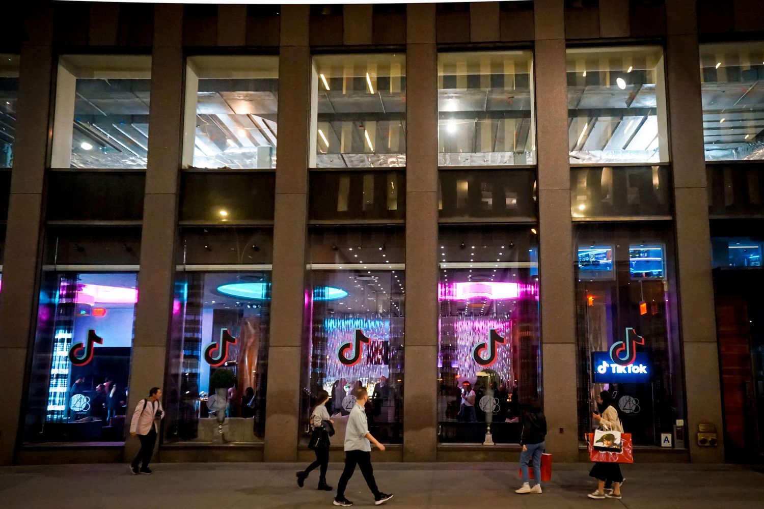 Long covered walkway with illuminated columns and neon lighting.
