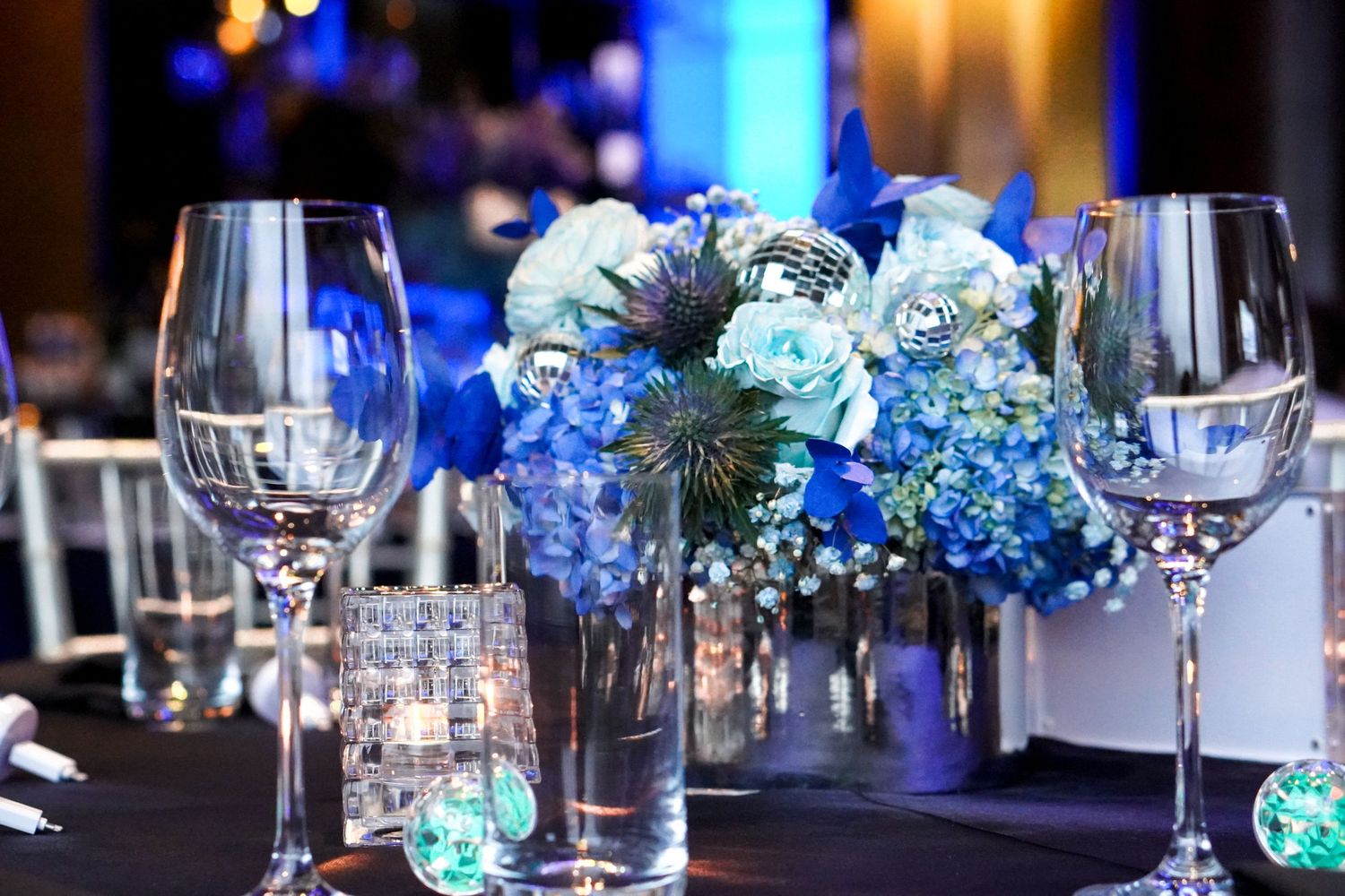 Elegant table setting with blue hydrangea centerpiece and wine glasses.