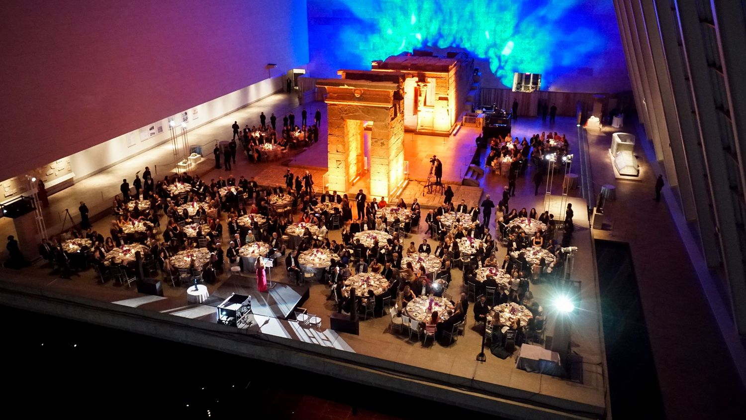 Aerial view of an elegant ballroom reception with round tables and dramatic lighting.