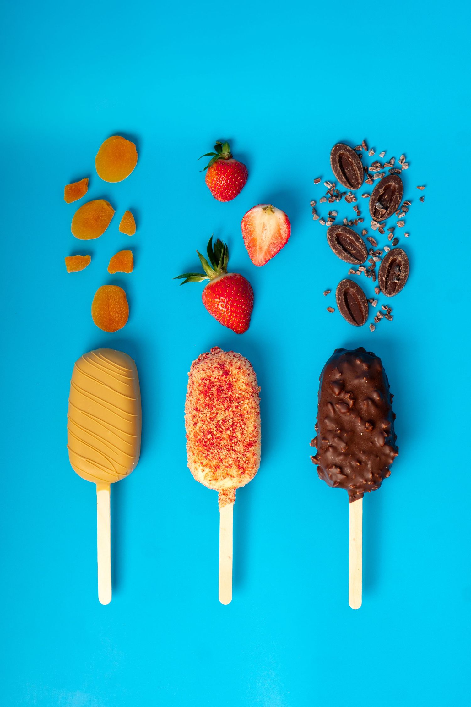 Three ice cream bars showing almond, strawberry, and chocolate varieties with ingredients on blue background.