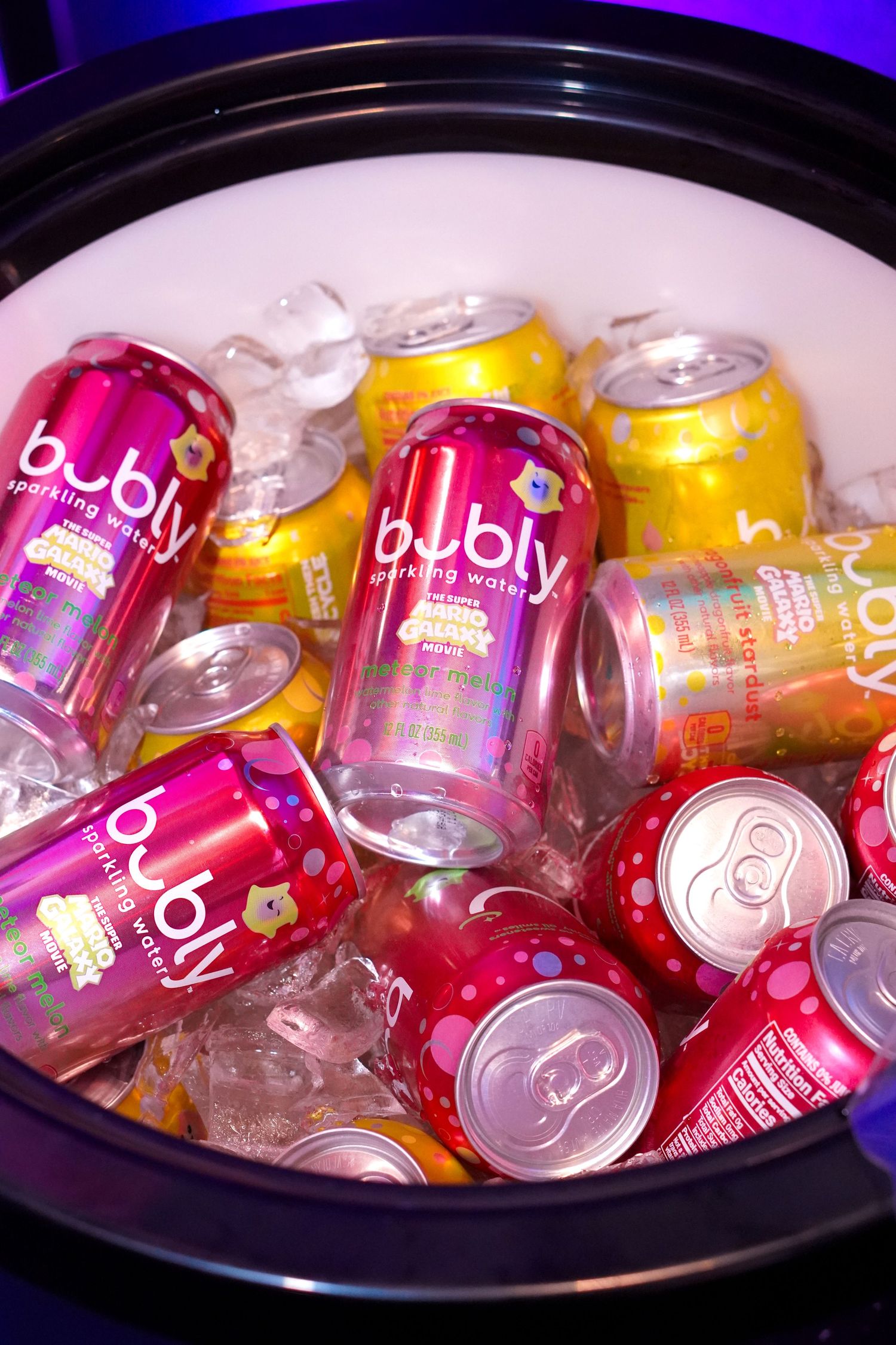 Assorted Bubly sparkling water cans chilling on ice in a large bowl at an event.