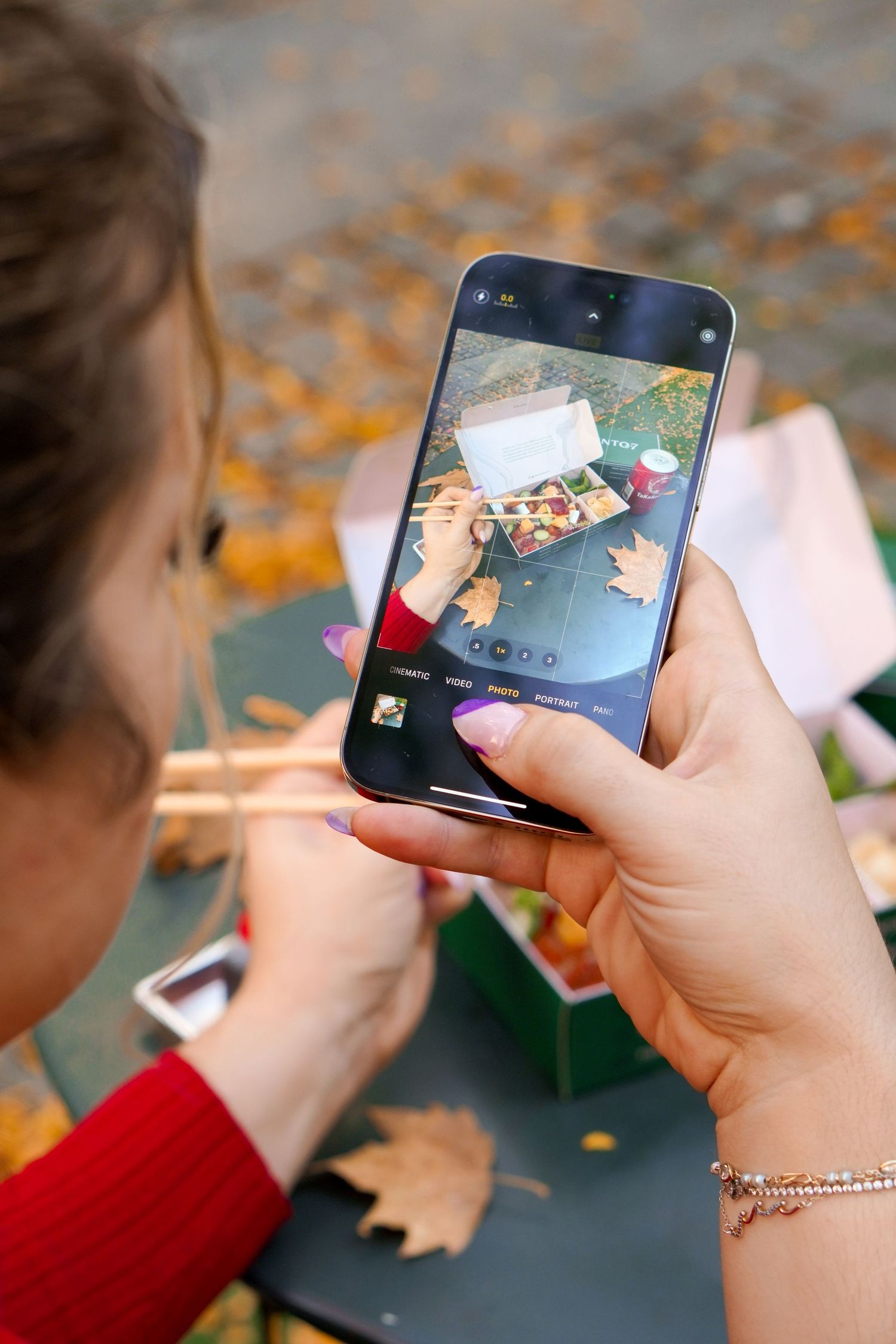 Hands holding smartphone and scrolling through photo gallery with festive items nearby.
