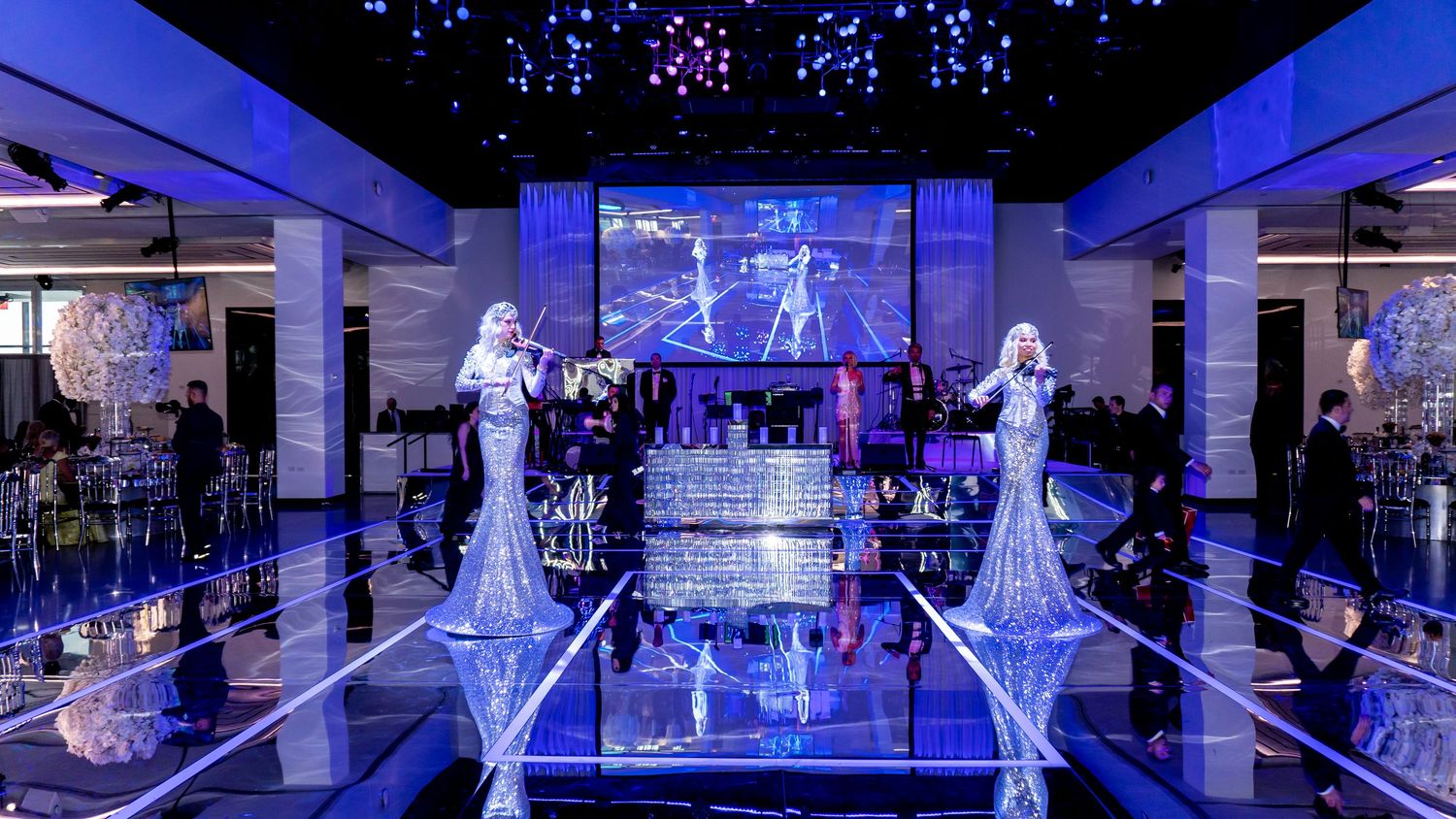 Modern event space with illuminated ceiling, reflective floors and video displays.