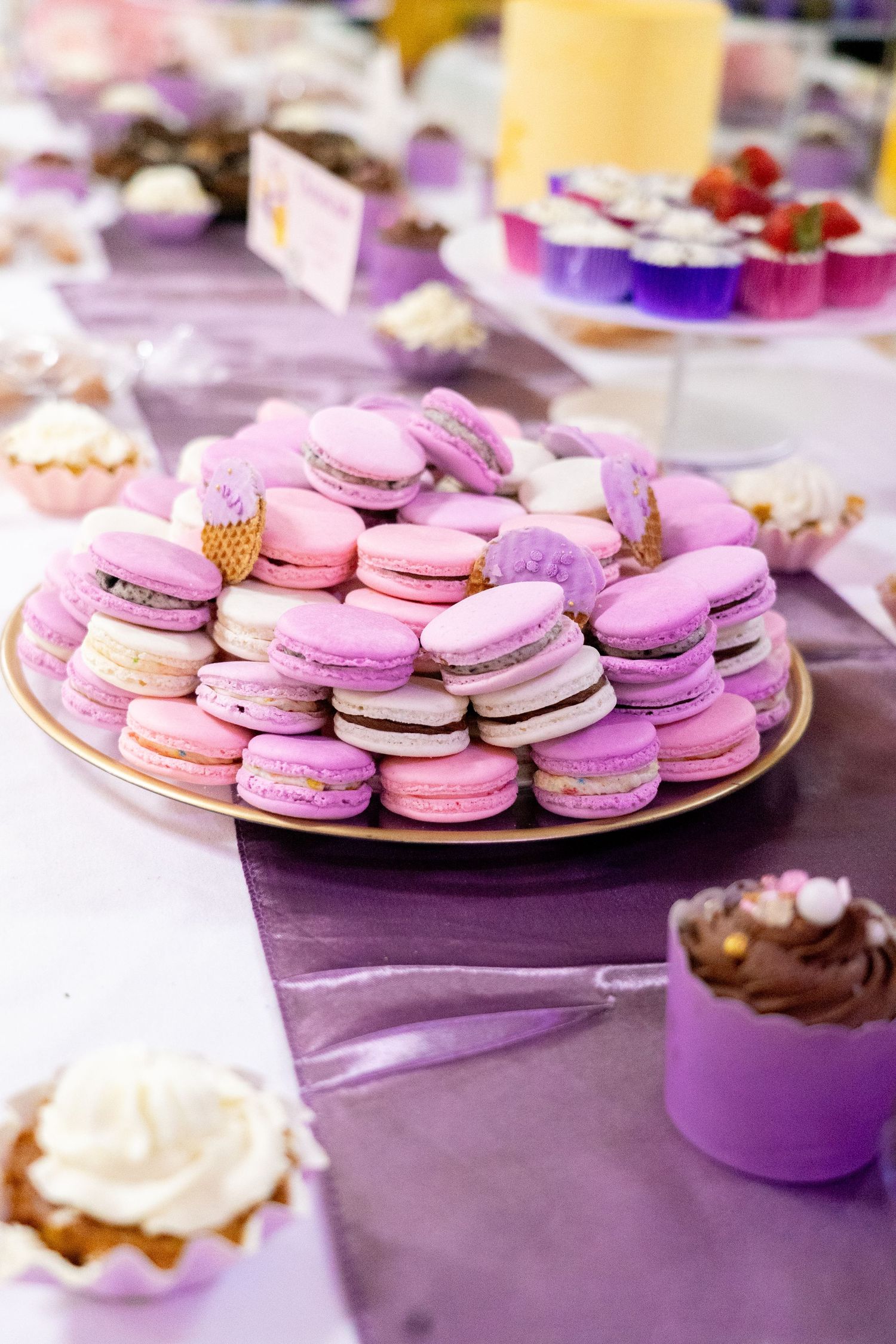 Colorful macarons in shades of pink and purple arranged on elegant serving plates.