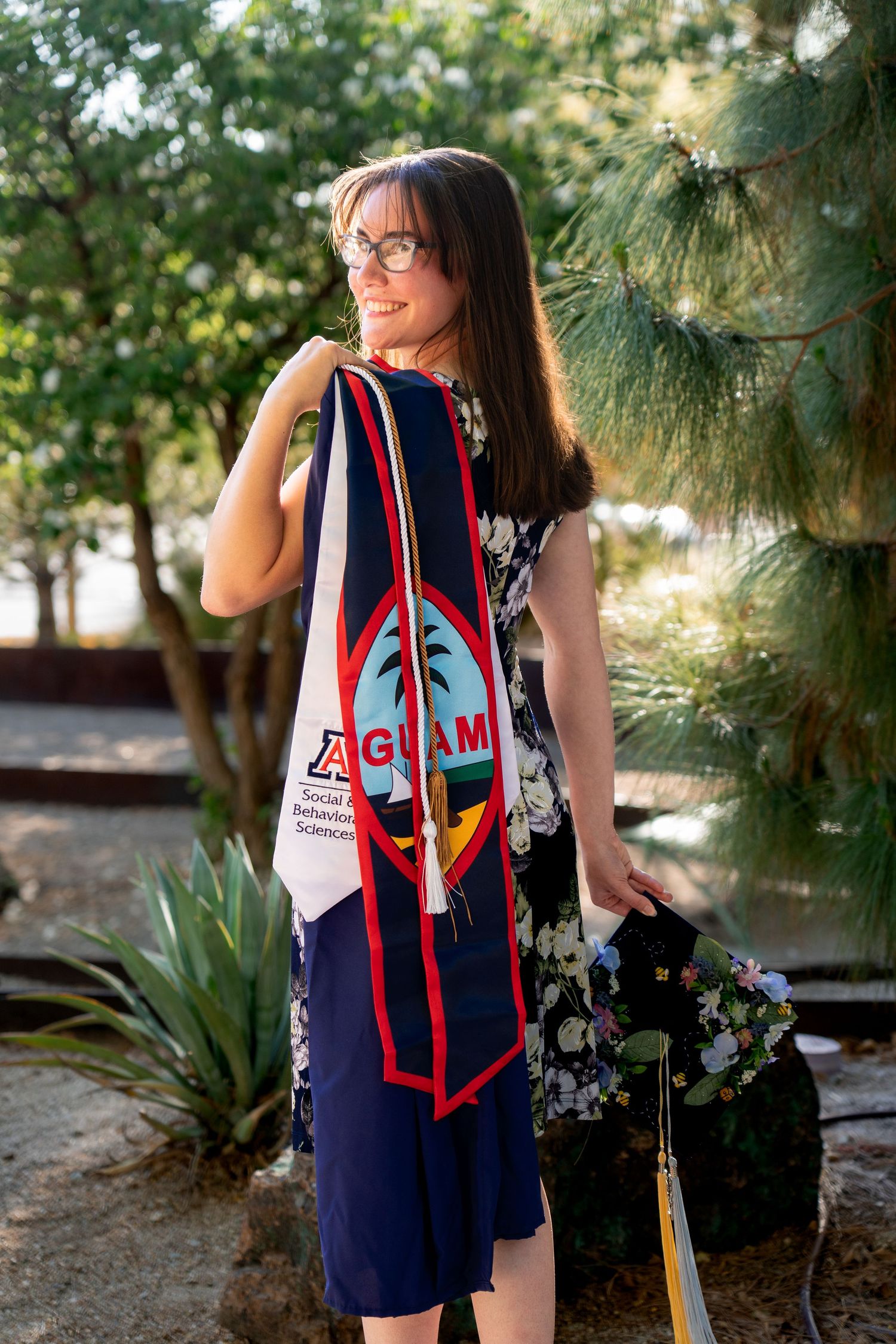 Navy and red patterned graduation attire photographed in garden setting.