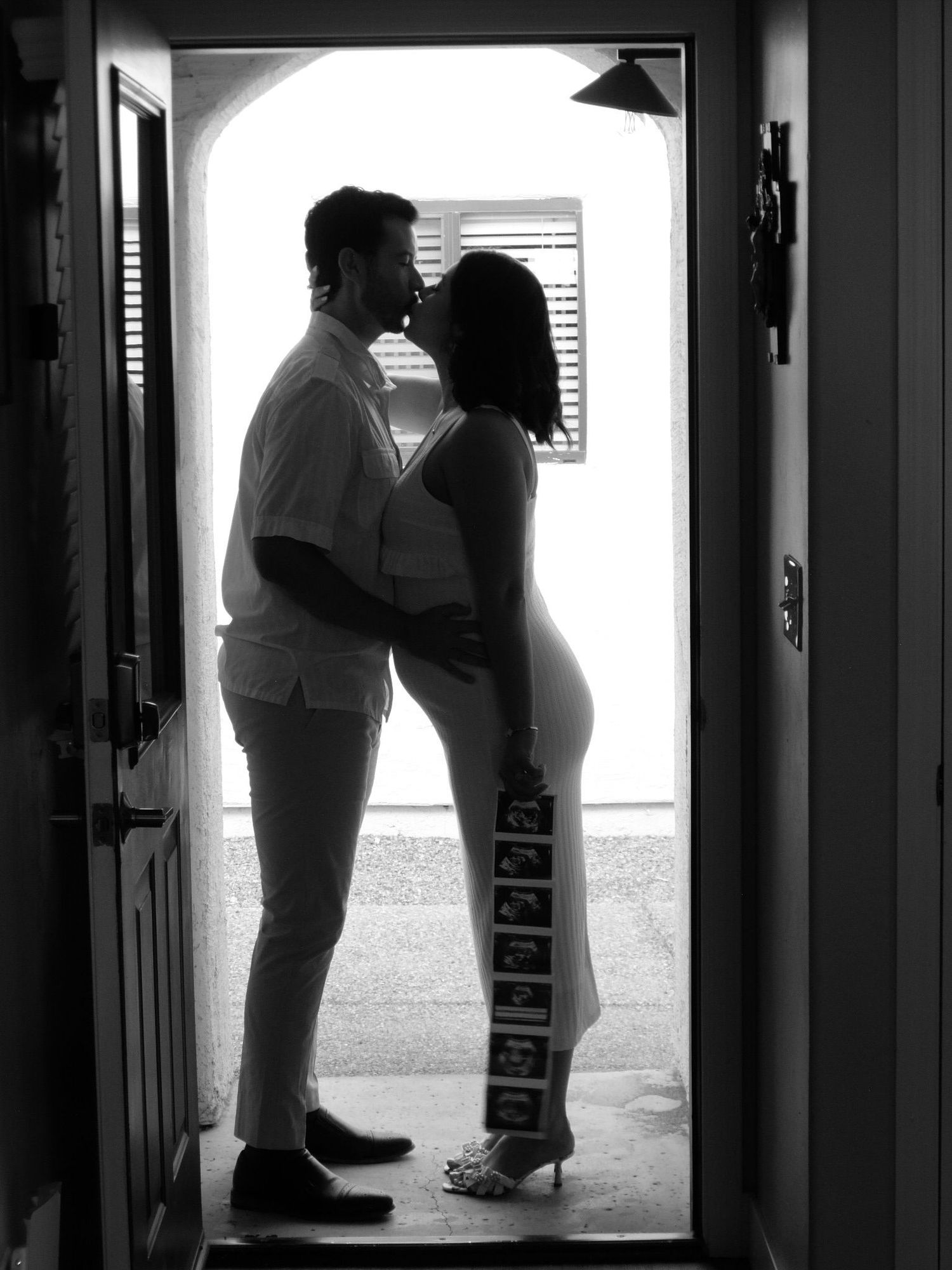 Black and white silhouette photos in hallway with dramatic lighting.