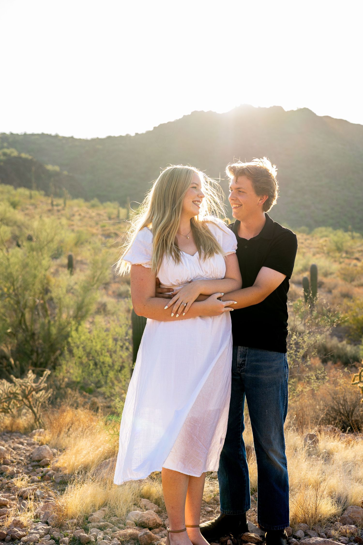 Couple embracing in desert landscape during golden hour sunset.