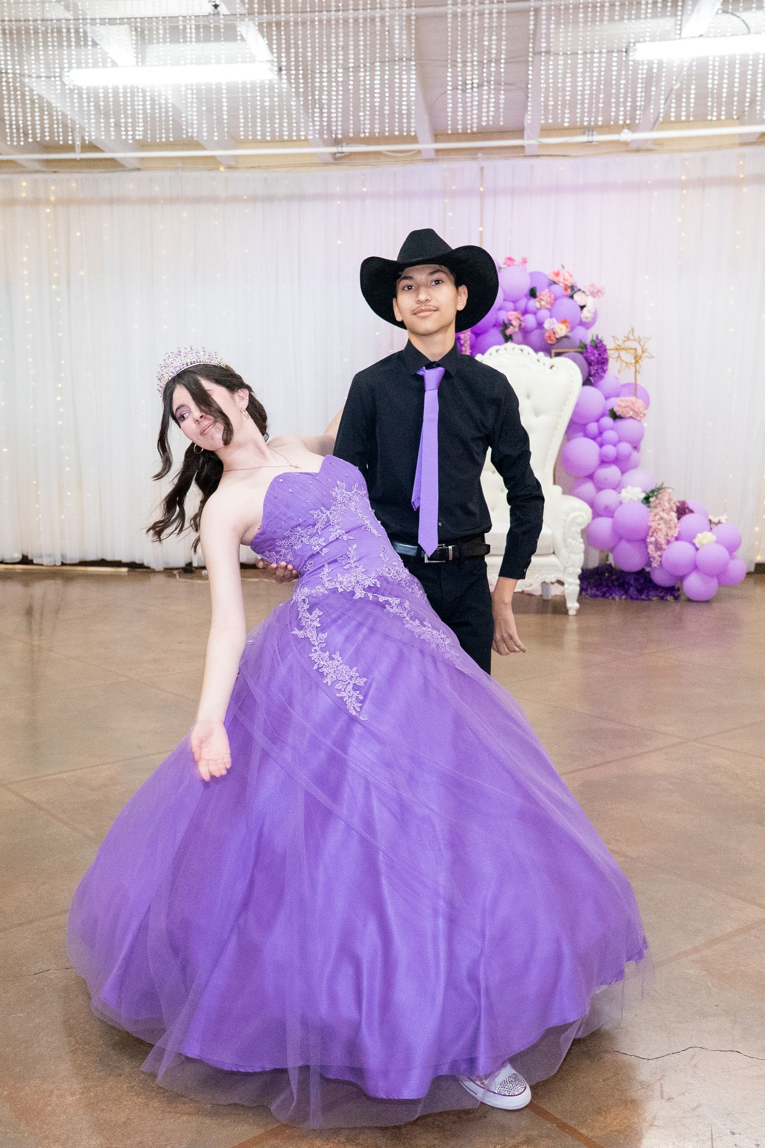 Celebration scene with people in purple formal attire posing against balloon decorations.