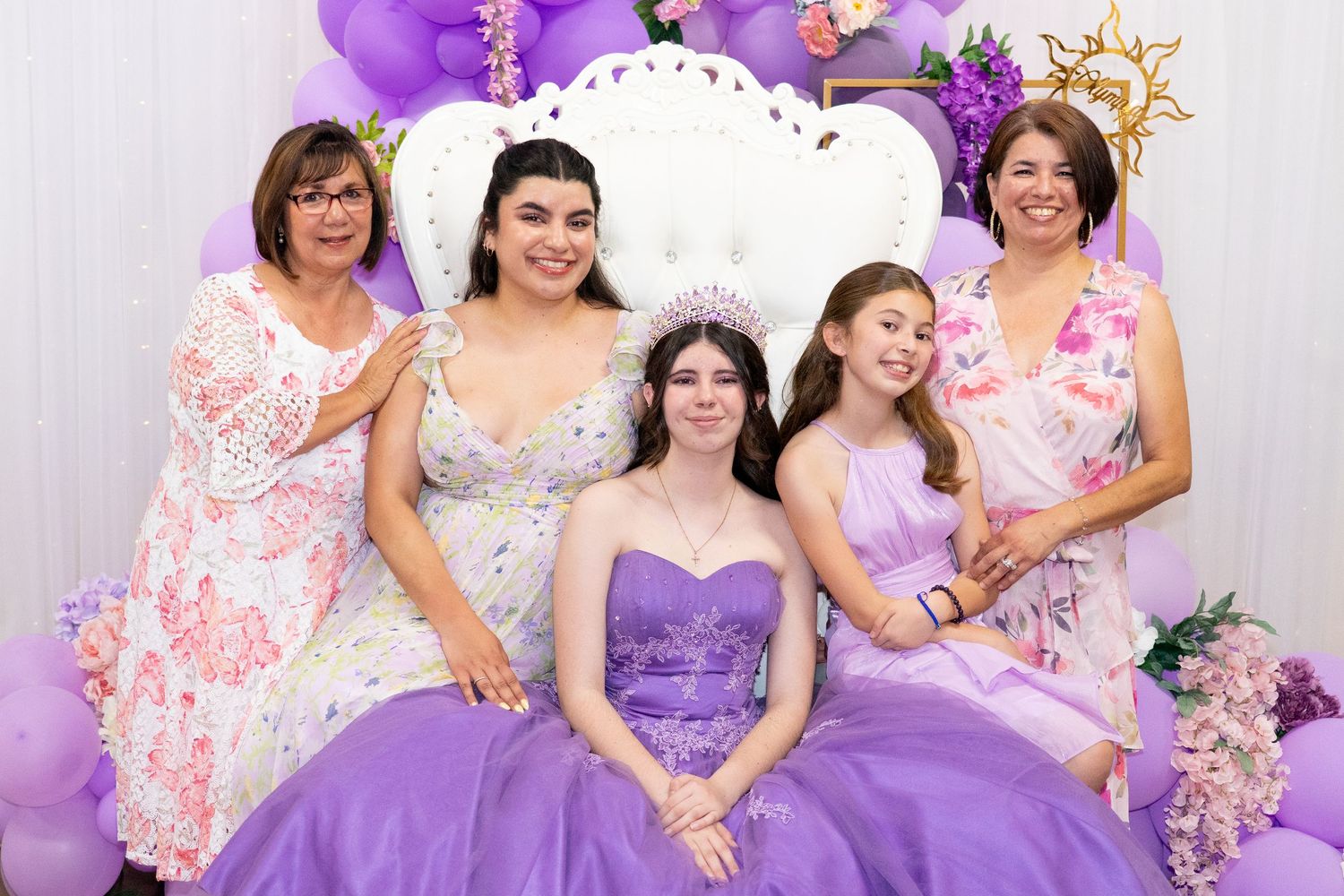 Group photo featuring family and floral accents at a Quinceañera celebration.