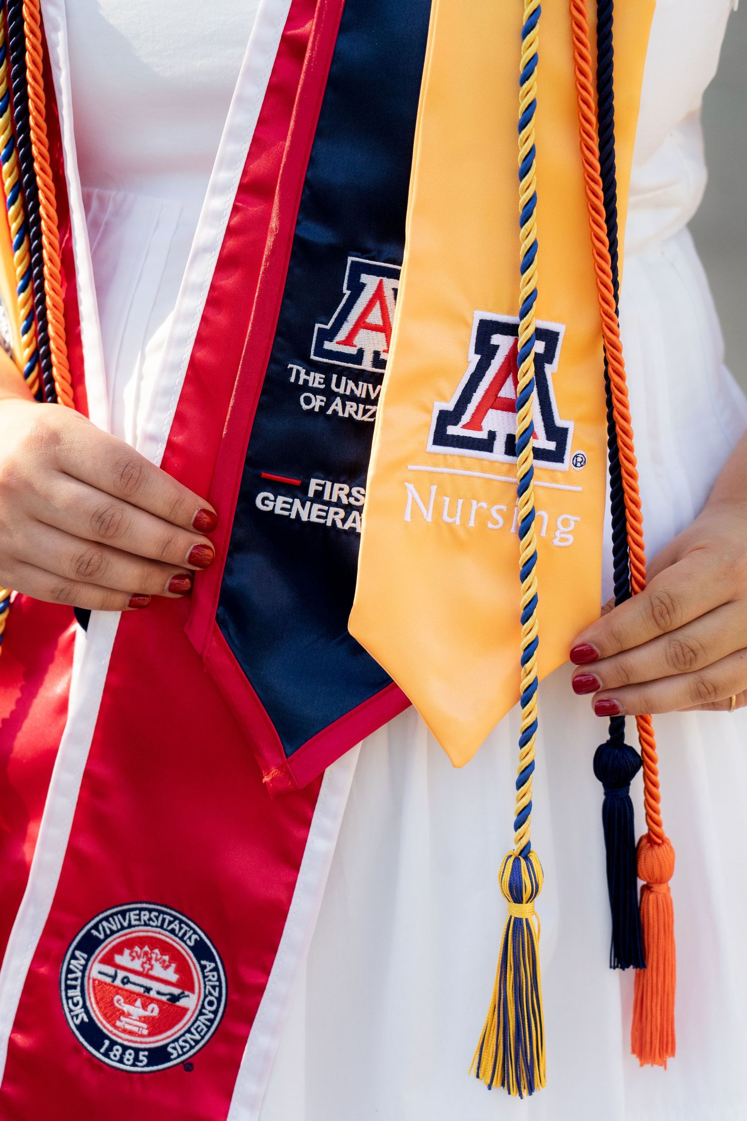 Close-up of graduation stoles showing University of Arizona nursing program insignias and tassels.