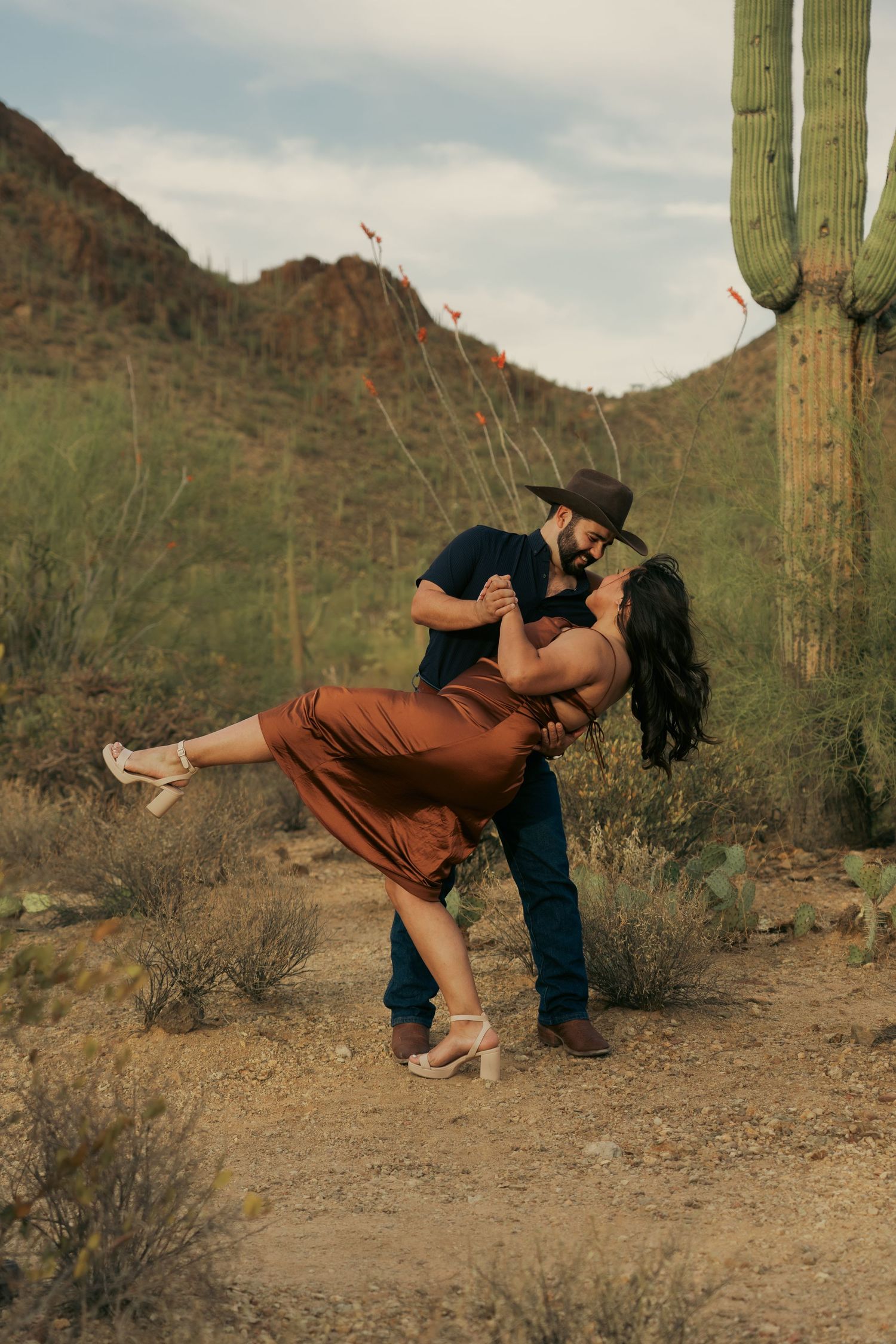 A romantic desert photoshoot with saguaro cacti and mountains in the background.