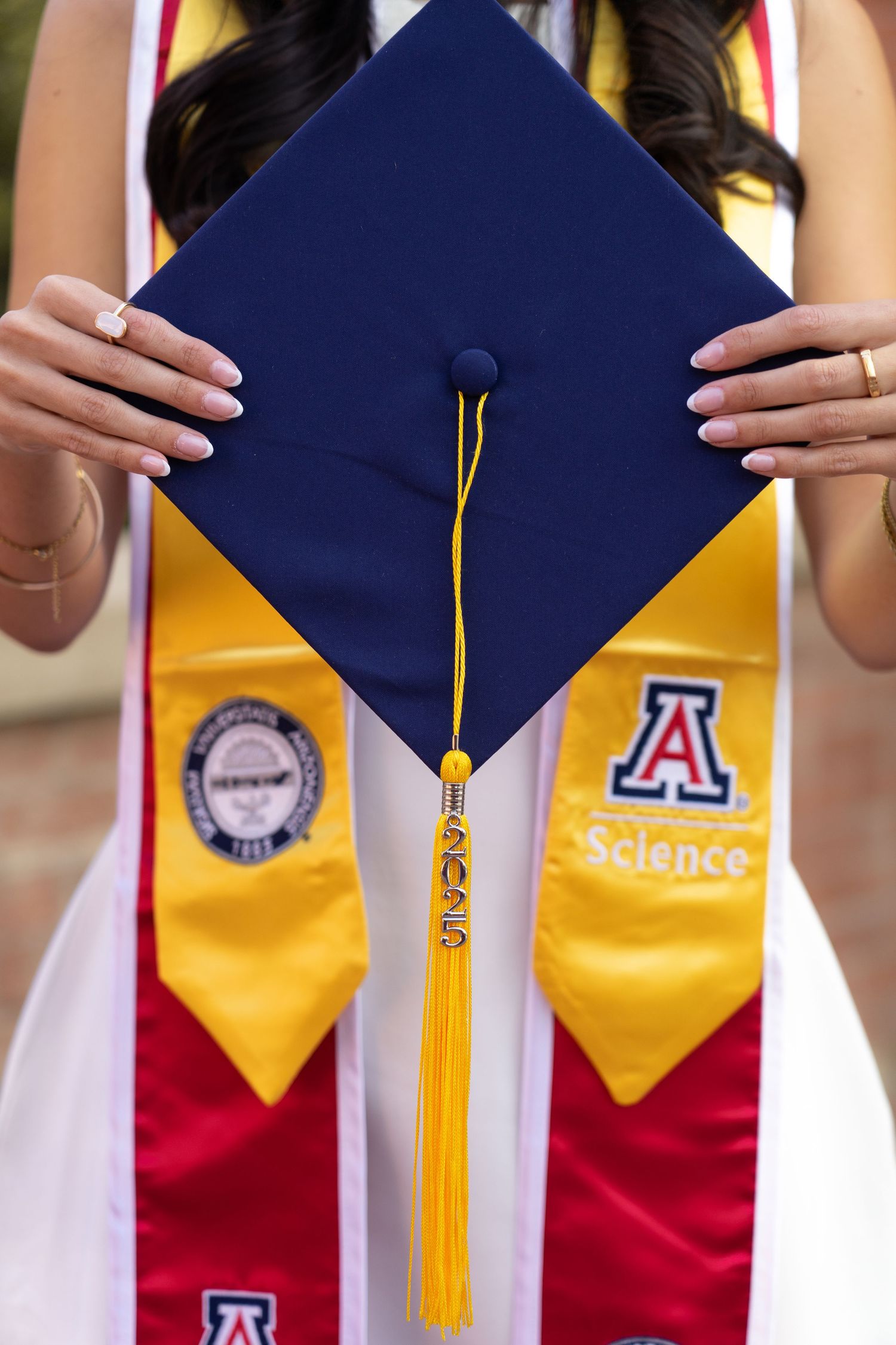 Detail shots of navy graduation cap with gold tassel and University of Arizona emblems.