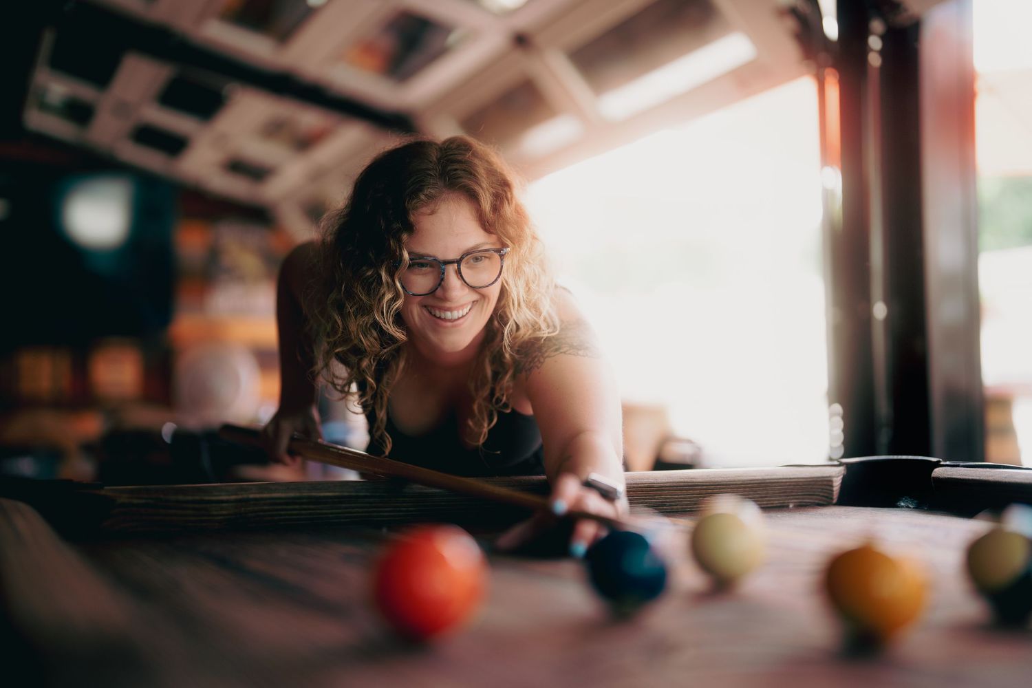 Pool balls lined up on a billiards table in warm indoor lighting.