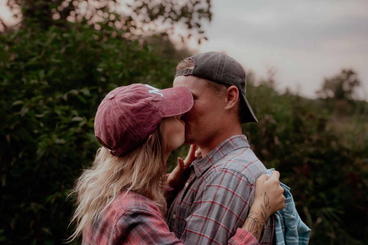 A romantic couple embraces among autumn trees and foliage on a rural dirt road.