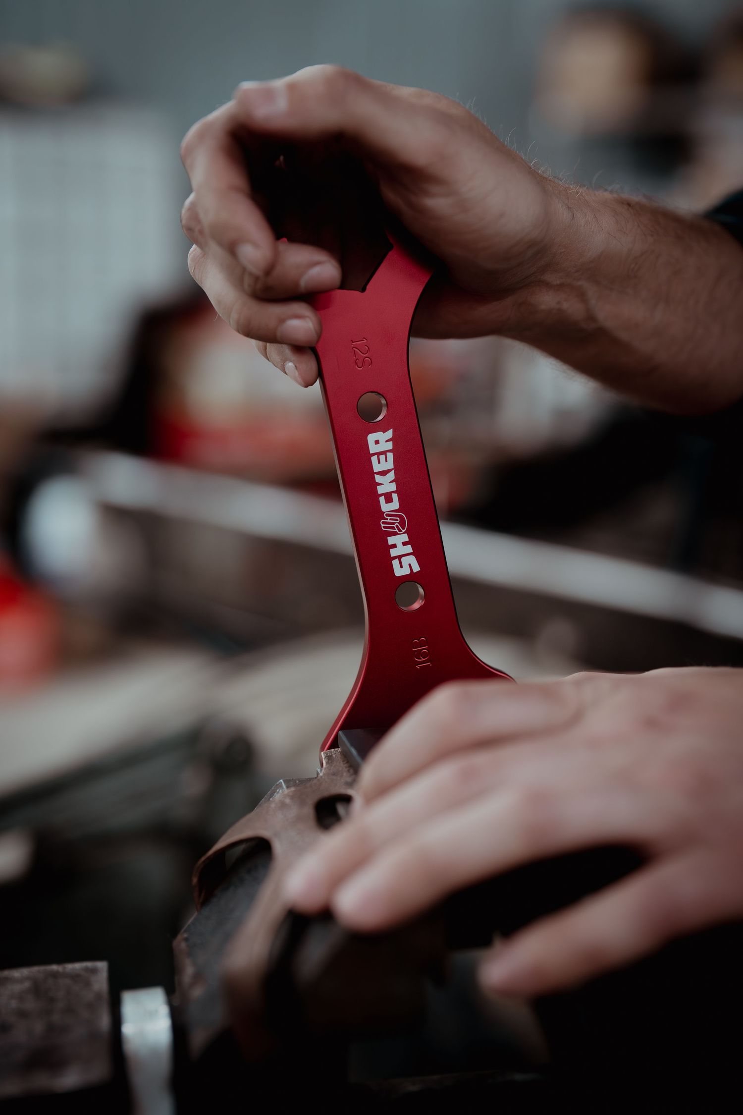 Close-up shot of hands holding red metal tool or measuring device.