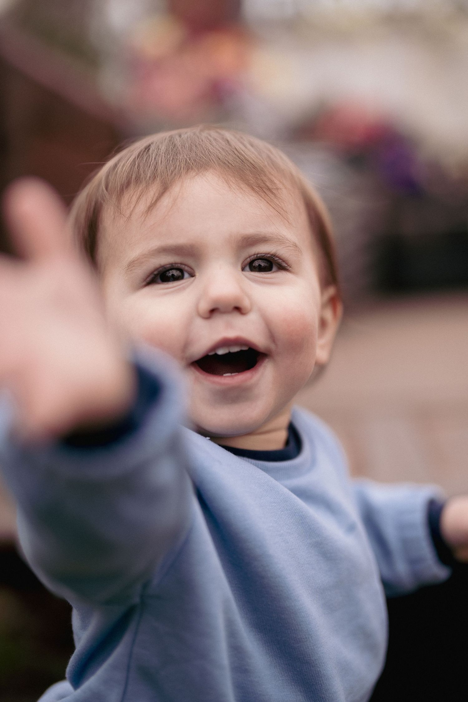 Young child in blue sweater expressing joy and excitement.