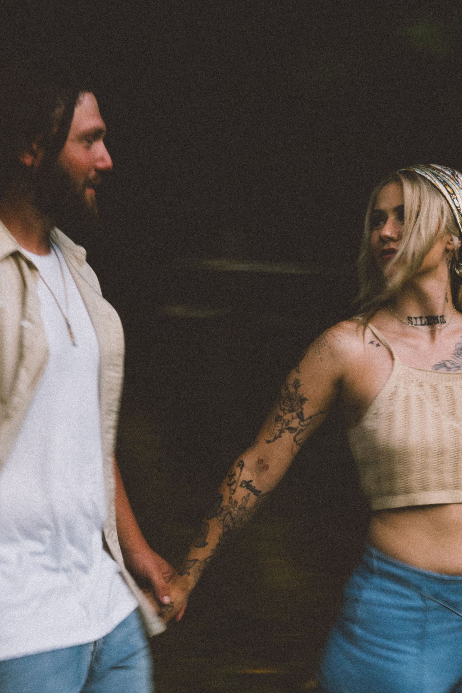 Artistic photo showing white clothing and tattoos in moody lighting.