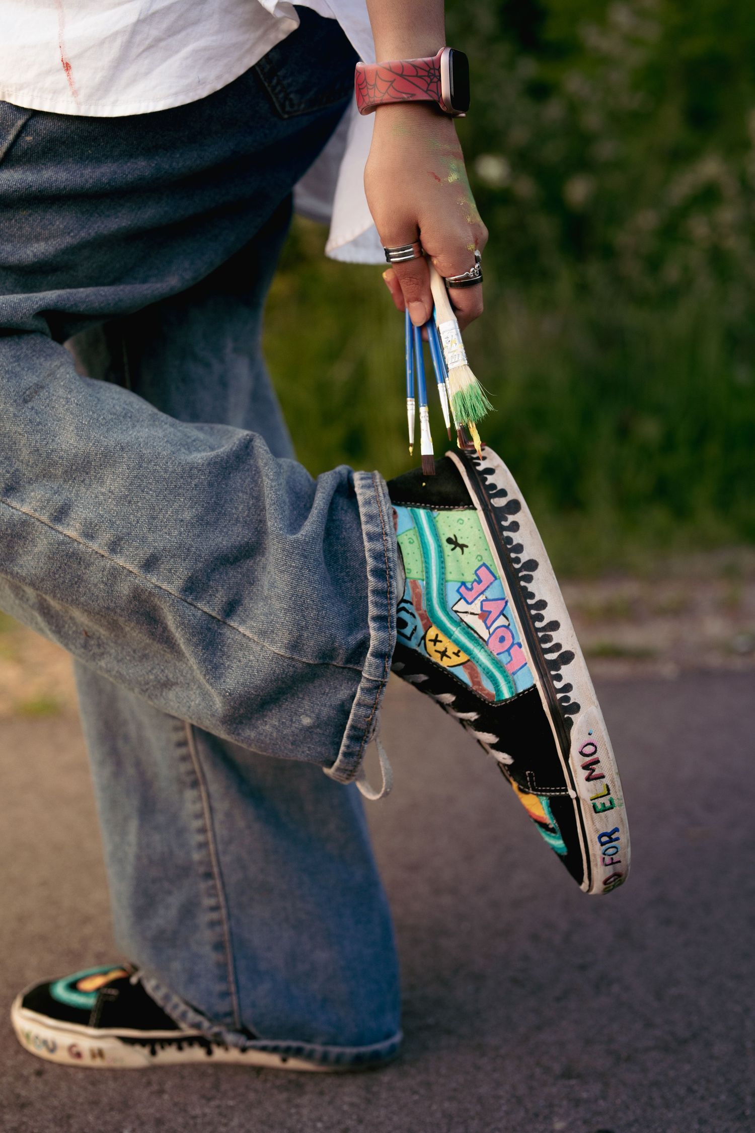 Close-up of colorful decorated sneakers worn with blue jeans.