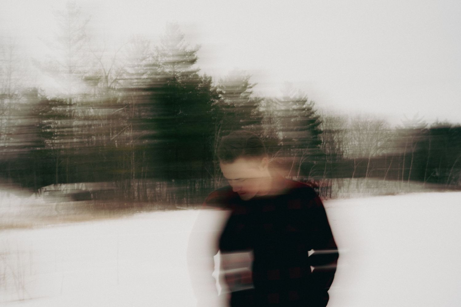Blurred motion photo of a person in black clothing with dreamy bokeh trees in the background.