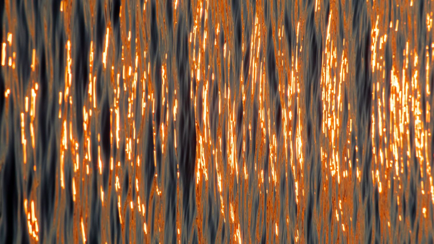 Vertical streaks of golden sunlight reflecting off rippling water creating a dazzling pattern.