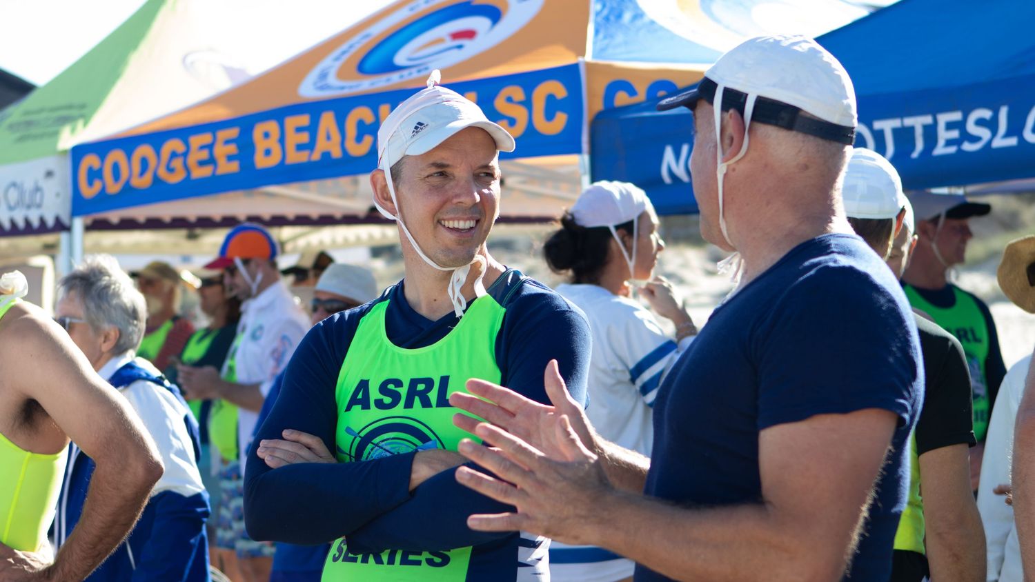 Smiling athlete in ASRL vest chatting at Coogee Beach Surf Club competition.