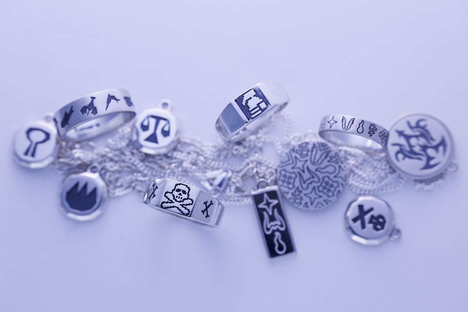 Silver rings and engraved charms collection with zodiac symbols and skull motifs.