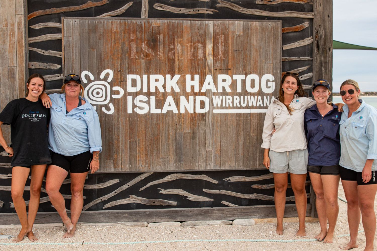 Group of women posing in front of Dirk Hartog Island Wirruwana wooden sign at the Western Australia landmark.