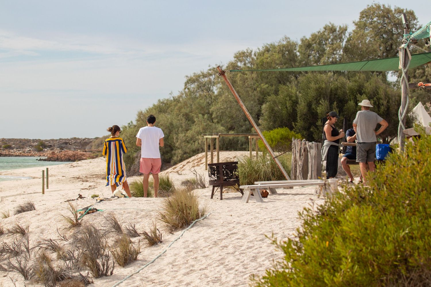 Small group of visitors enjoying beach activities on white sand dunes with native scrub at Dirk Hartog Island.