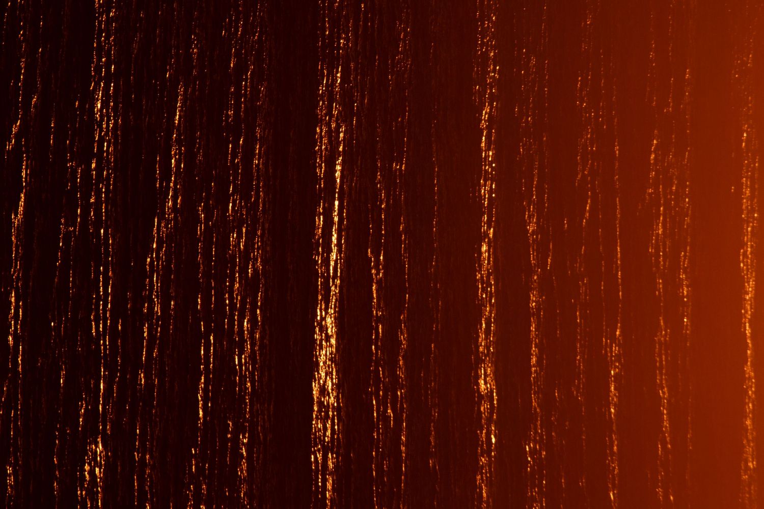 Abstract dark red and orange streaks of light creating vertical lines on a dark background.