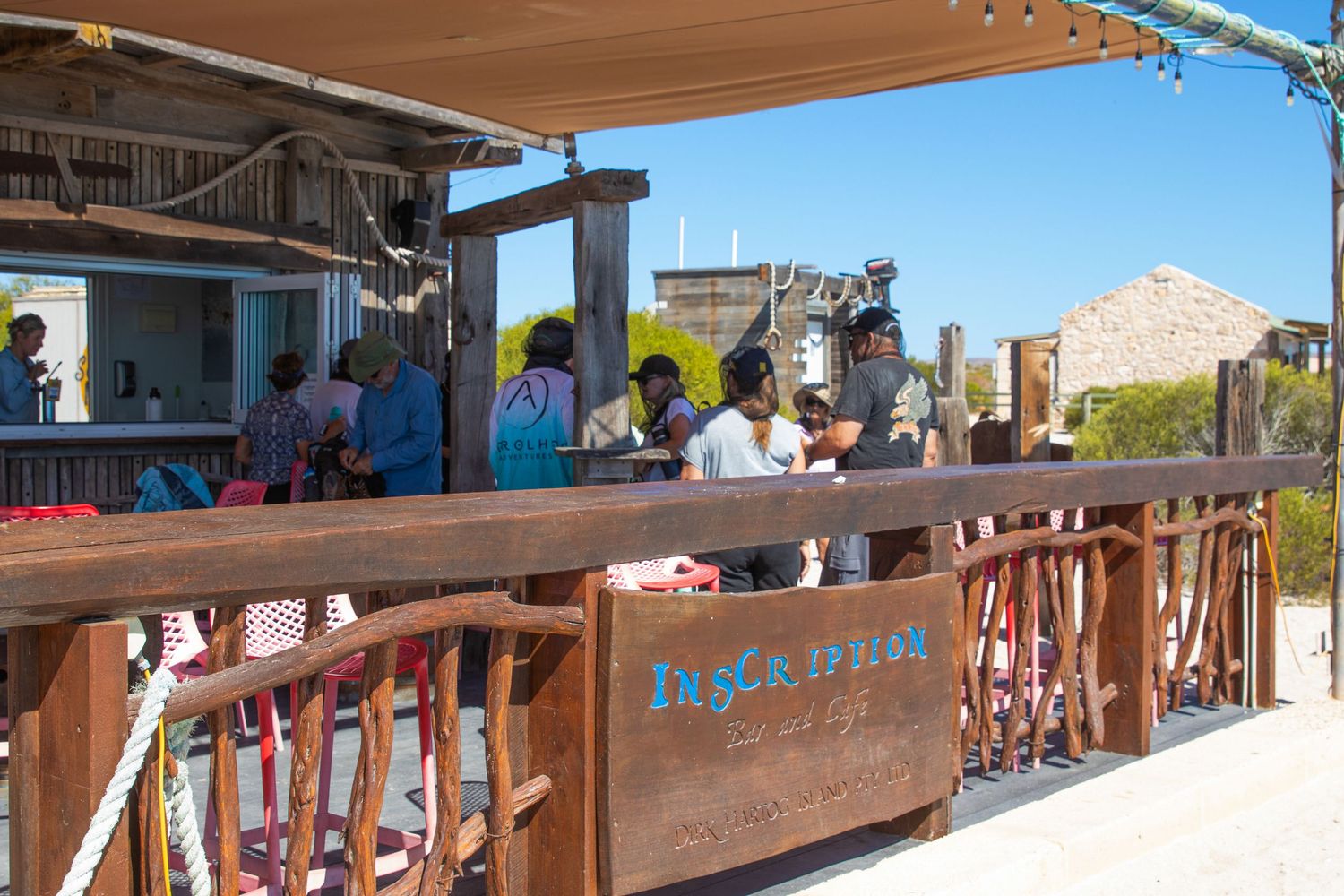 Visitors enjoying drinks at the outdoor Inscription Gin bar on a sunny day.