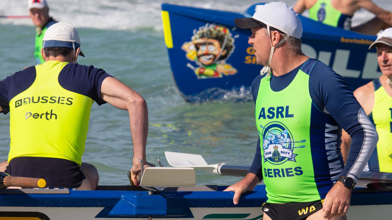 Two ASRL Series surf boat competitors prepare for a race on a bright sunny Australian beach day.