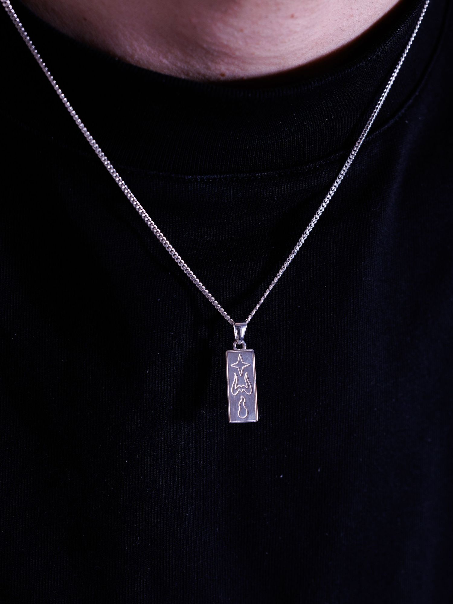 Silver rectangular bar pendant necklace with engraved star and flame design on a box chain.
