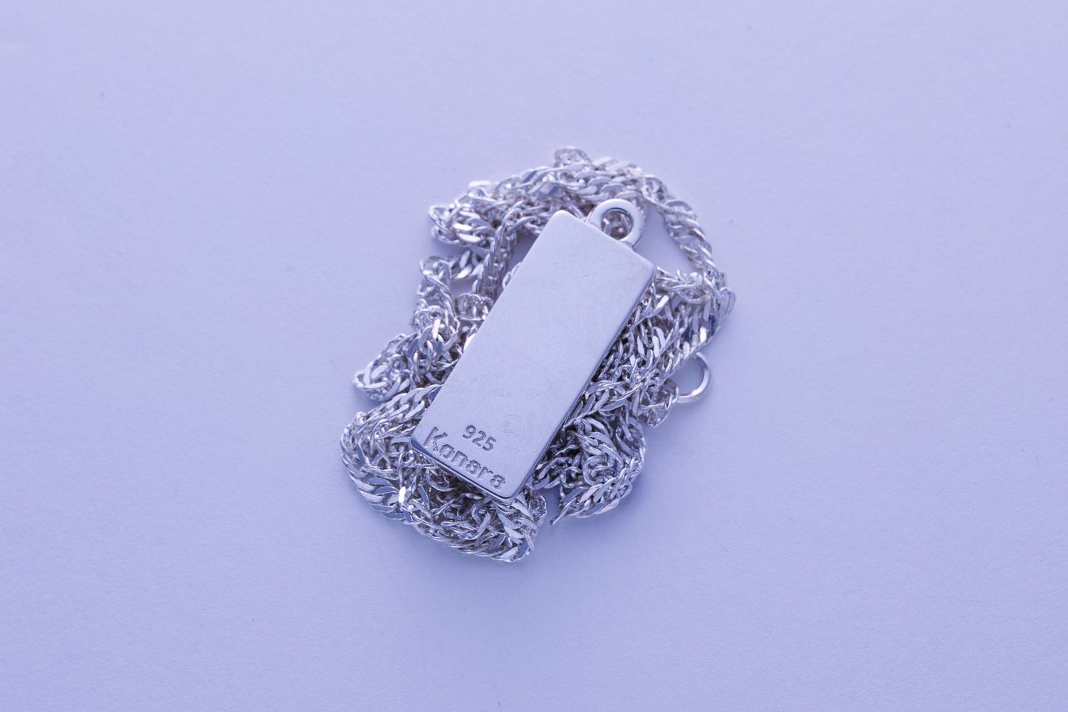 Plain rectangular silver pendant tag with stamped 925 marking on twisted rope chain.