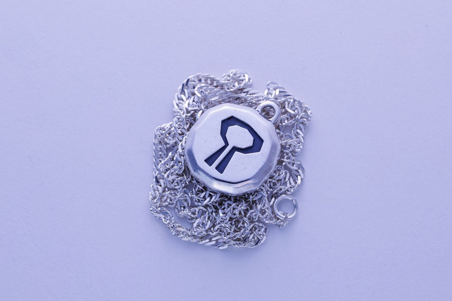 Round silver pendant necklace with engraved keyhole design on delicate silver chain.