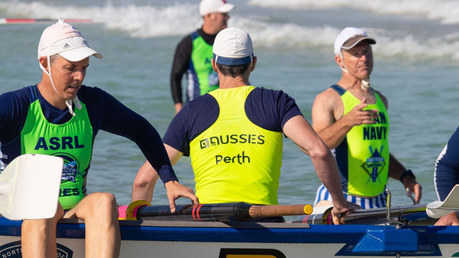 ASRL Series and Boussес Perth surf boat rowers prepare their boat on the beach before a race.