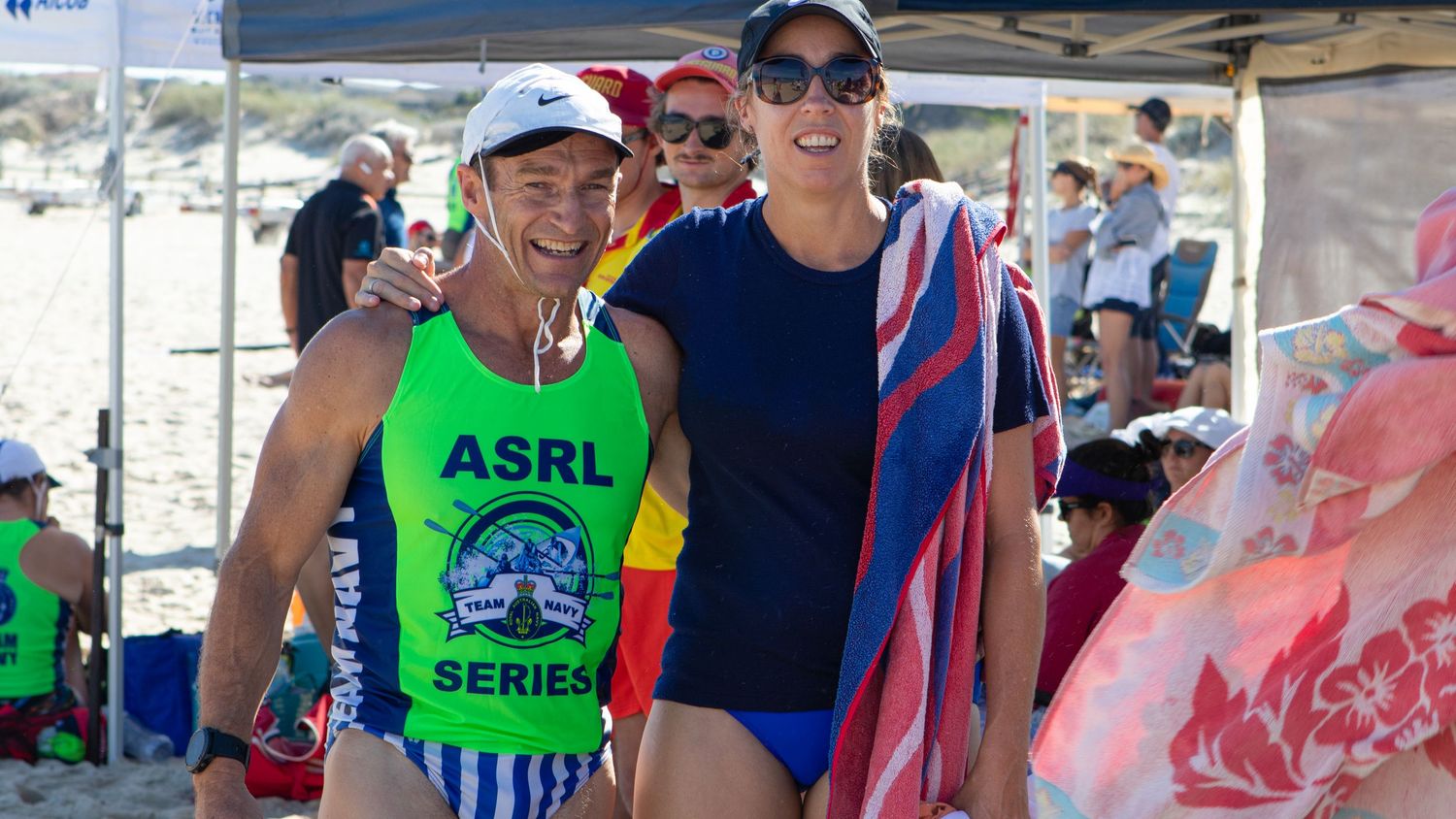 Two female surf boat rowers smile together at an ASRL Series beach rowing event in Australia.