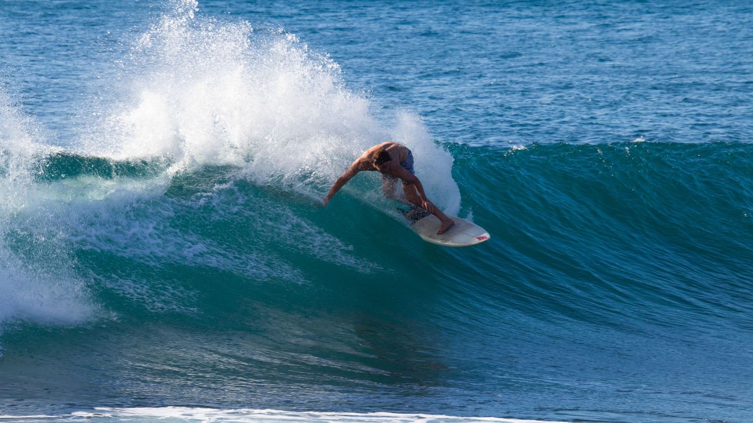 Surfer performing a sharp turn on a blue wave.