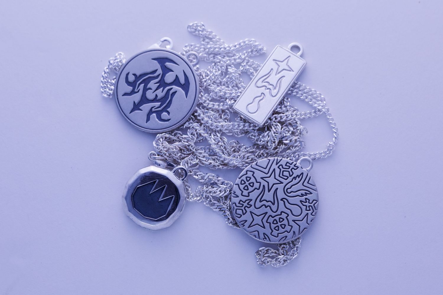 Collection of silver pendants and necklaces with tribal and decorative engravings.