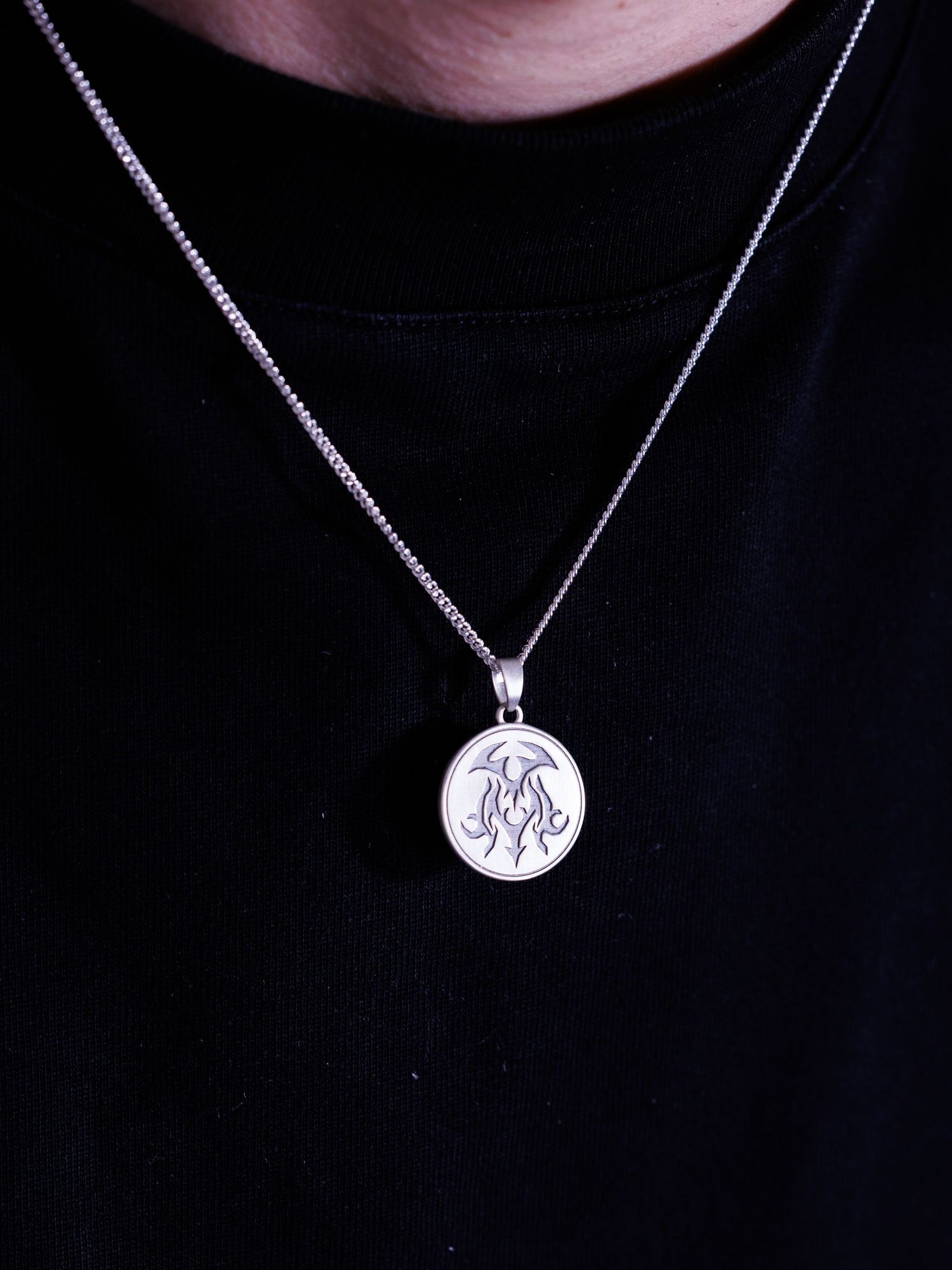 Silver circular pendant necklace featuring an engraved monogram design on a fine box chain.