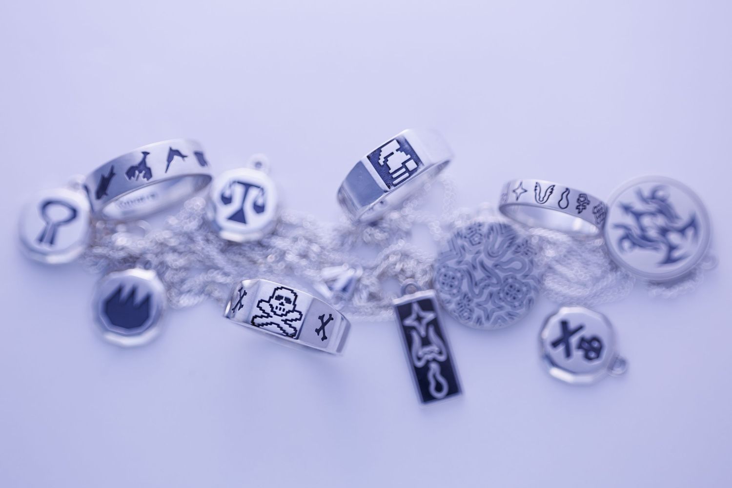 Collection of silver rings and charms with various symbols on white background.