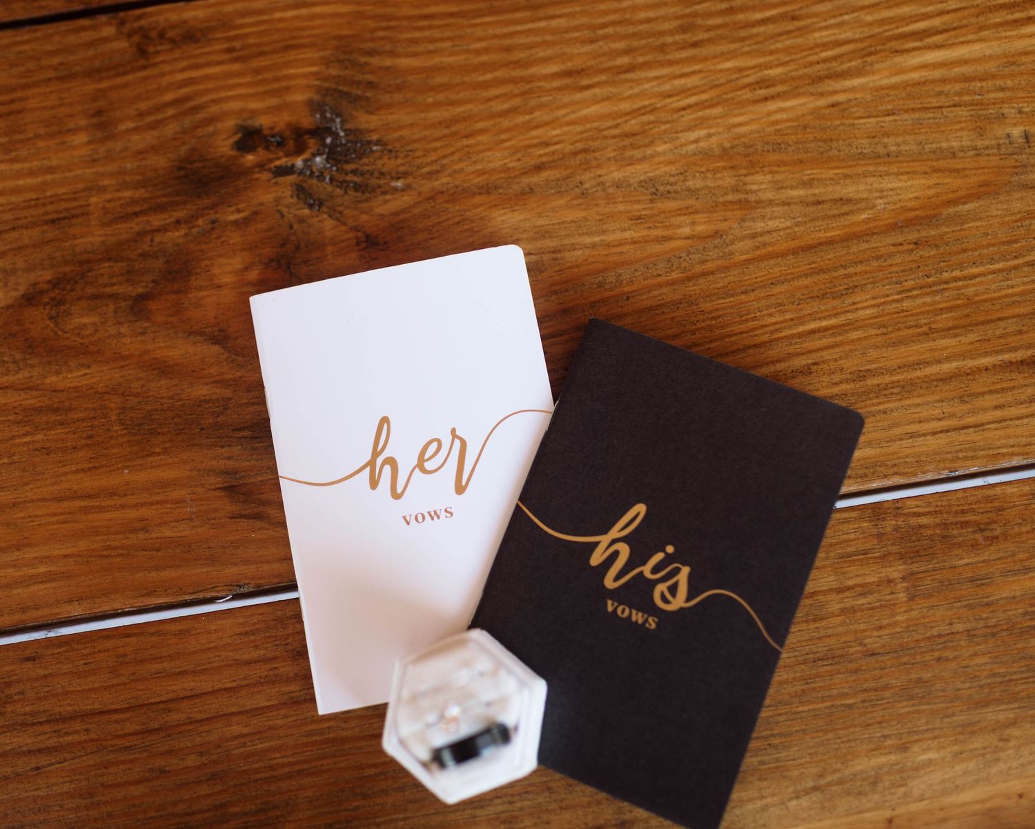 White and black wedding place cards with elegant calligraphy displayed on a rustic wooden table surface.