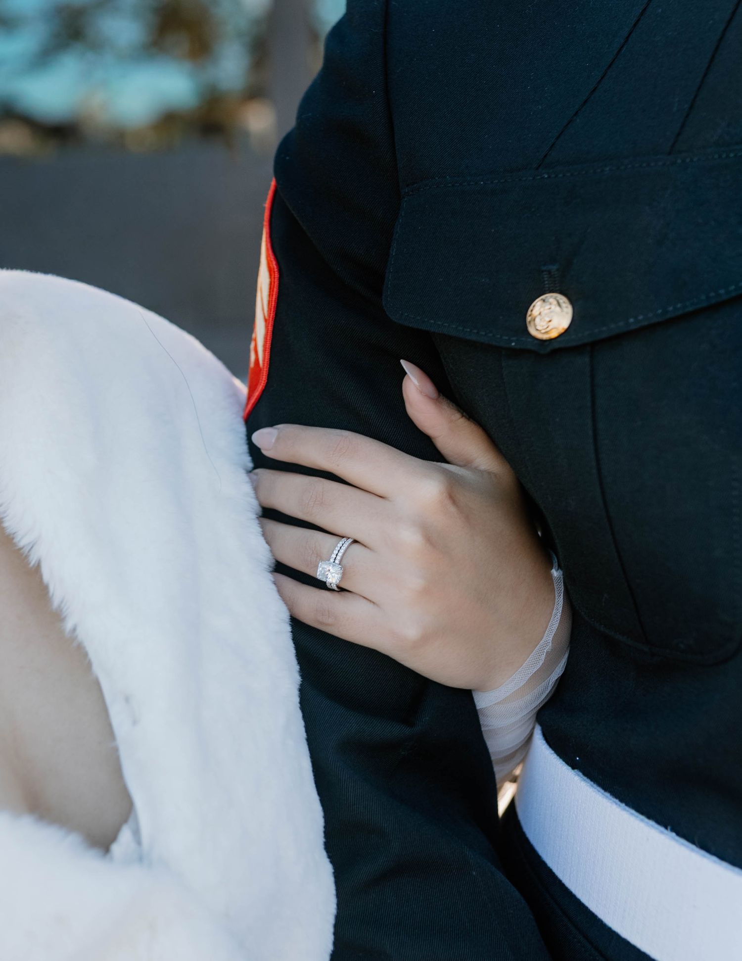 Close-up view of an elegant diamond engagement ring sparkling against a dark navy fabric background.