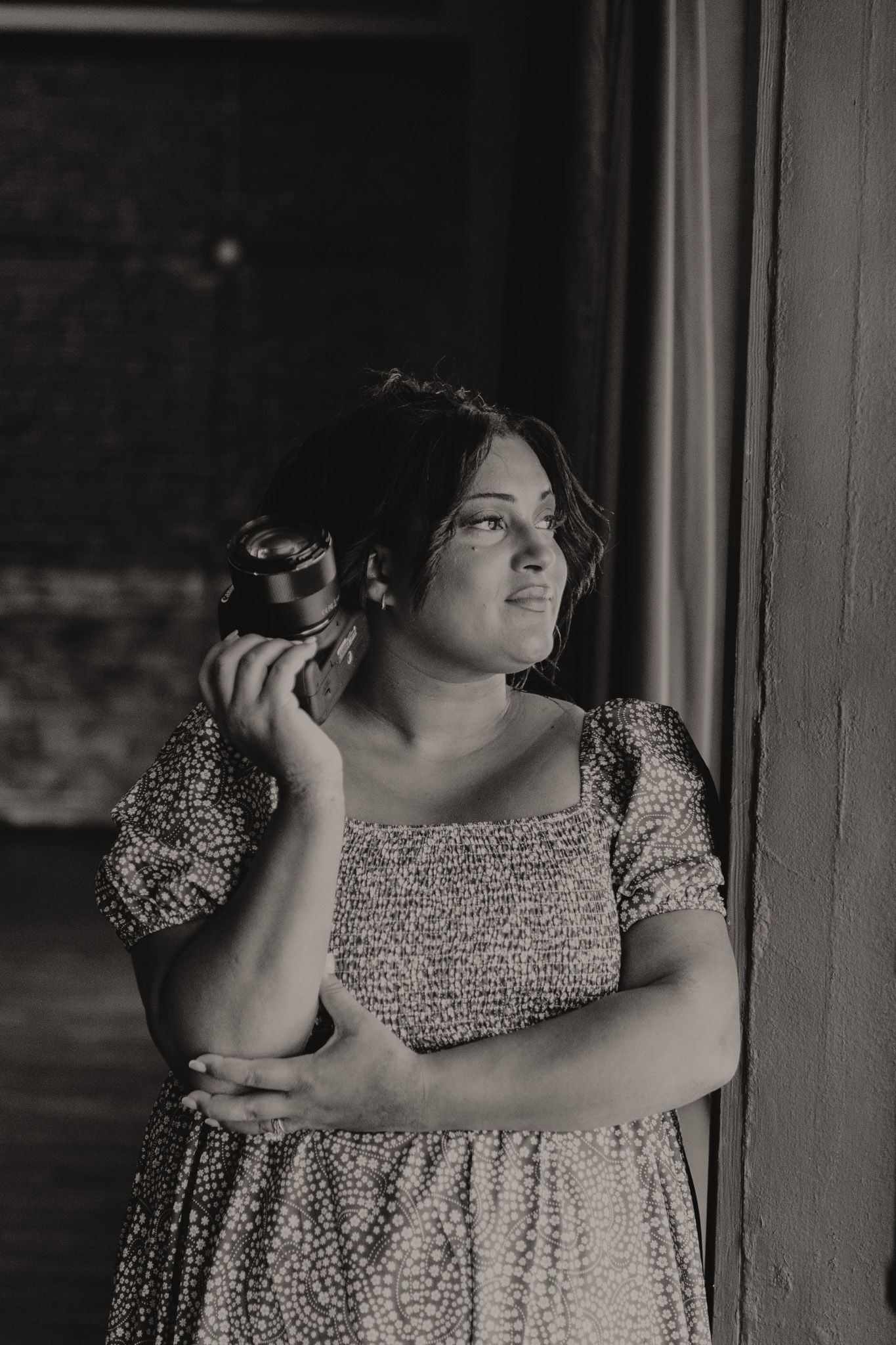 A person in a floral print dress poses against a wall in a series of black and white artistic portraits.